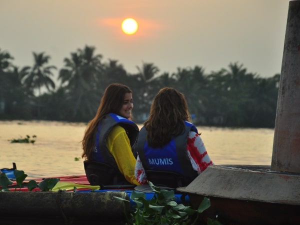 Two kayakers wearing life jackets beside the backwaters in low sunlight